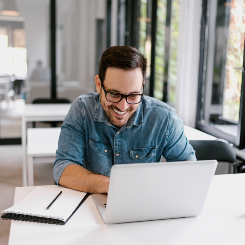 Focused man working on a laptop in a modern workspace, engaged in a productive task or online meeting.